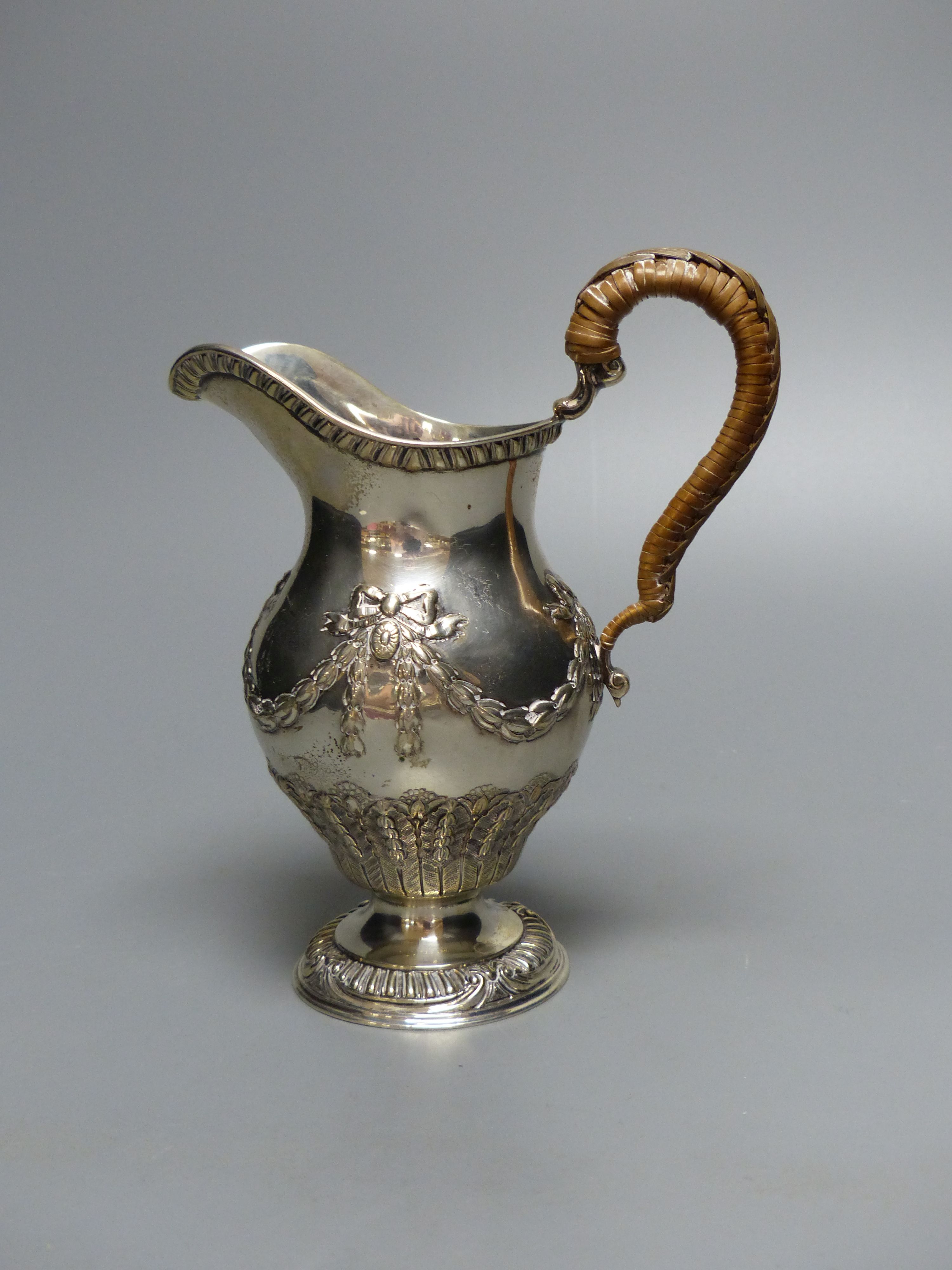 An Edwardian silver cream jug, with rattan handle, Goldsmiths & Silversmiths Co Ltd, London, 1909, 15.5cm, 8oz.